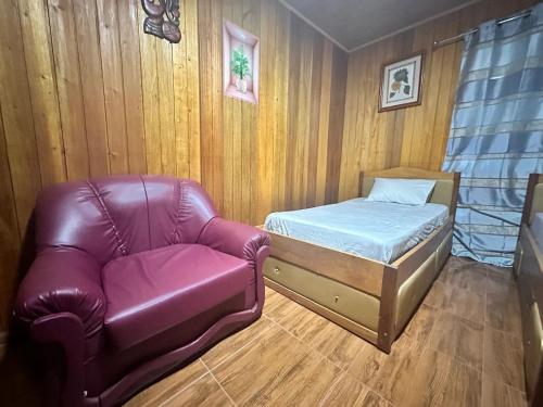 a bedroom with a couch and a bed and a chair at Pensão Aragão & Lima in São Tomé