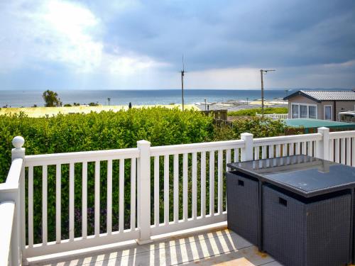a white porch with a trash can and the beach at Apple Grove 110 - Ukc9393 in Exmouth