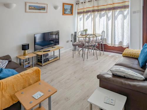 a living room with a couch and a tv and a table at Sandy Cott in Kilkhampton