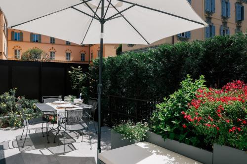 a patio with a table with an umbrella and flowers at La Terrazza - Private Jacuzzi in Downtown Como in Como