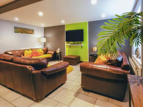 a living room with two leather couches and a plant at St Hildas Rest in Hinderwell