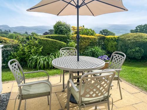 a table and chairs with an umbrella on a patio at Fron - Cottage in Mynfford