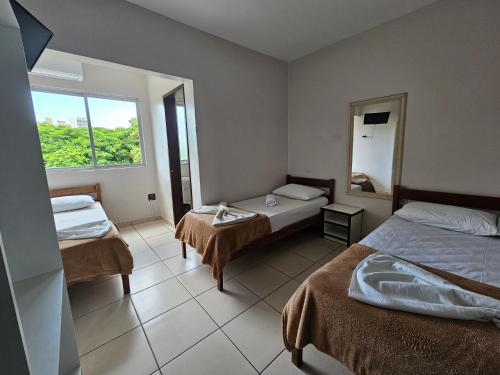 a hotel room with two beds and a mirror at Ok Inn Hotel Express in Tubarão