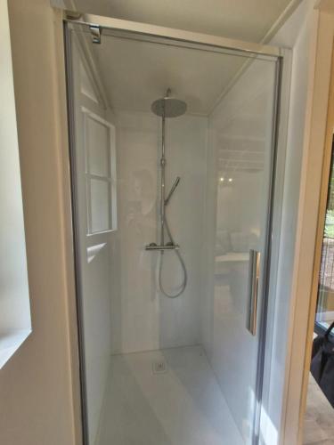 a shower with a glass door in a bathroom at In het sprookjesbos in Zonnebeke