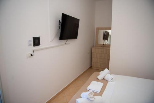 Ein weißes Zimmer mit Handtüchern und einem Flachbildfernseher. in der Unterkunft Deve Mar Hotel in Borsh