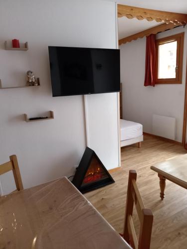 a living room with a fireplace with a tv on the wall at Résidence les églantines in Le Mélézet