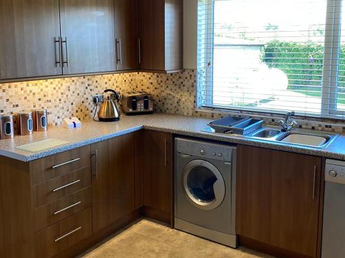 a kitchen with a washing machine and a sink at White Towers - Hw7625 in Llandwrog