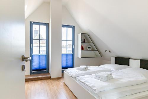 a white bedroom with two beds and two windows at Strandmuschel in Born