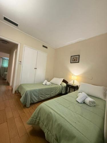 two beds in a hotel room with green sheets at Hotel Hernandarias in Santa Fe