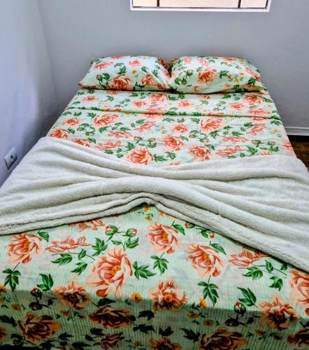 a bed with a blanket on top of it at Casa no centro de Poços de Caldas in Poços de Caldas