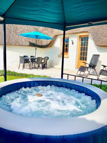 a large hot tub with a table and an umbrella at Chaumière cosy avec SPA Baie de somme in Abbeville