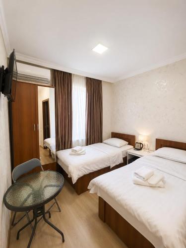 a hotel room with two beds and a chair at Hotel Maria in Tbilisi City