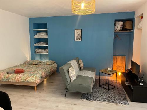 a bedroom with a blue wall with a bed and a chair at APPARTEMENT HYPER CENTRE - Place du Minage in Angoulême