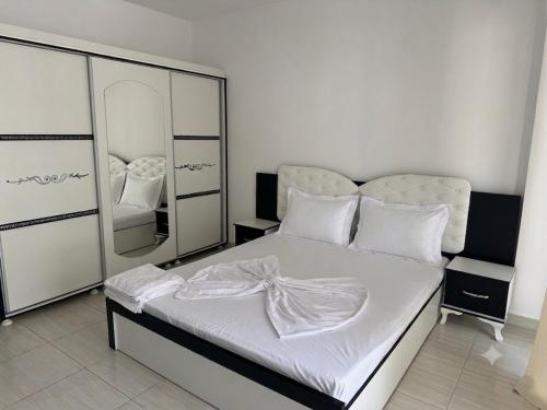 a bedroom with a white bed with a mirror at Sea & Mount apartament in Shëngjin