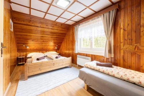 two beds in a room with wooden walls at Chaloupka u Borovků in Vyskeř