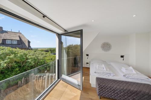 a bedroom with a bed and a balcony at Strandwächter in Hörnum