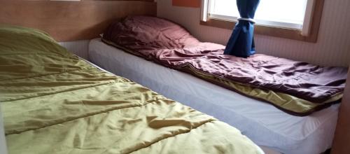 a unmade bed in a room with a window at le 130 mobile home à Meschers sur Gironde au camping L'escale in Meschers-sur-Gironde