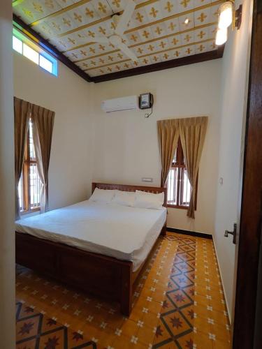 a bedroom with a bed and two windows at Vriksha Heritage Farm Stays in Sethumadai