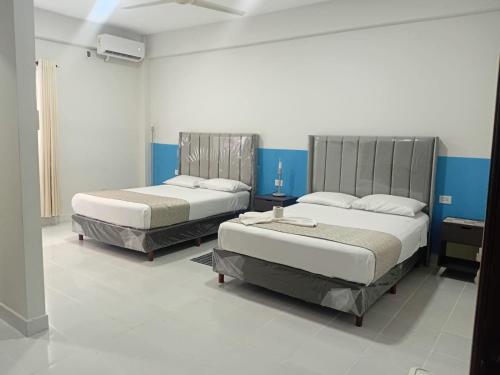 two beds in a room with blue and white walls at Hostal Center A in Santa Cruz de la Sierra