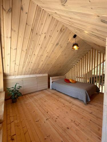 a bedroom with a bed in a wooden ceiling at Jūrmalciema Pērle AMBER in Jūrmalciems