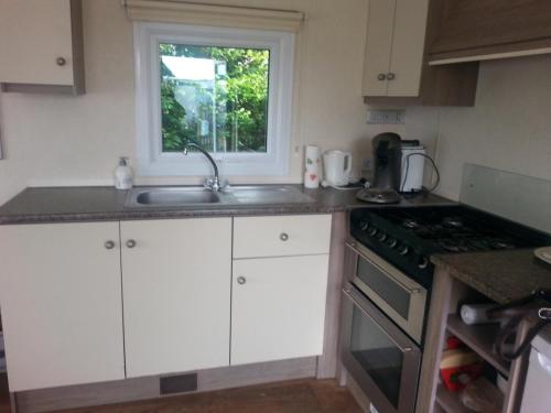 a kitchen with white cabinets and a sink and a window at VZ779 Stacaravan in Wemeldinge in Wemeldinge