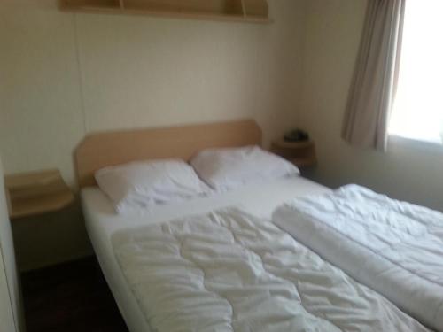 an unmade bed in a bedroom with a window at VZ779 Stacaravan in Wemeldinge in Wemeldinge