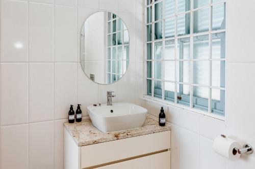 a white bathroom with a sink and a mirror at Duifie in Paternoster