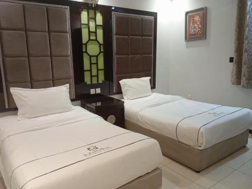a room with two beds and a table and windows at جولدن نيو الدار للشقق المخدومة in Jazan