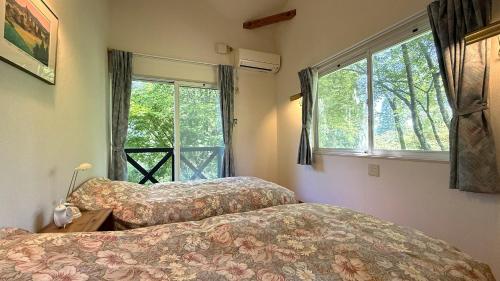 two beds in a room with a window at Garden Villa Minamiaso in Minami Aso