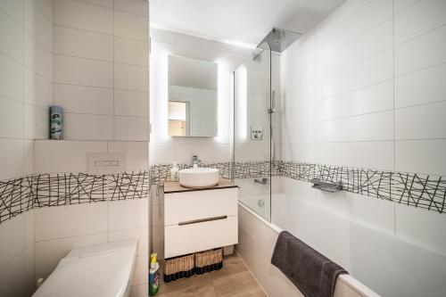 a white bathroom with a sink and a tub at Alpine ski apartment - Petit Chatel in Châtel