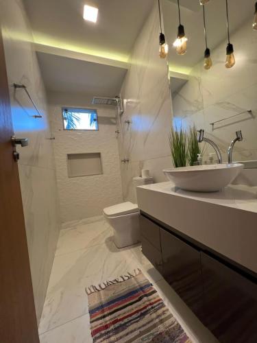 a white bathroom with a sink and a toilet at Apartamento amplo João VI in Muriaé