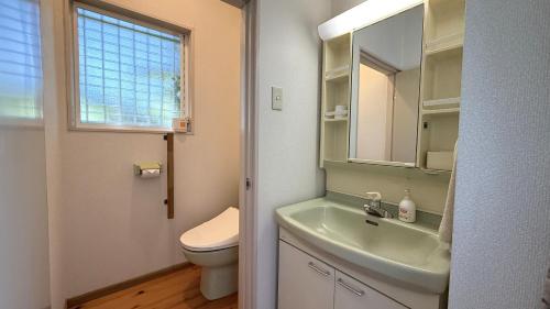 a bathroom with a sink and a toilet and a window at Garden Villa Minamiaso in Minami Aso