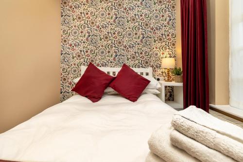 a bedroom with a white bed with red pillows at Hambleton House in Castle Donington