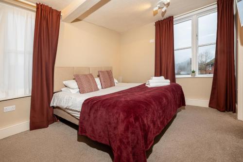 a bedroom with a large bed with red curtains at Hambleton House in Castle Donington
