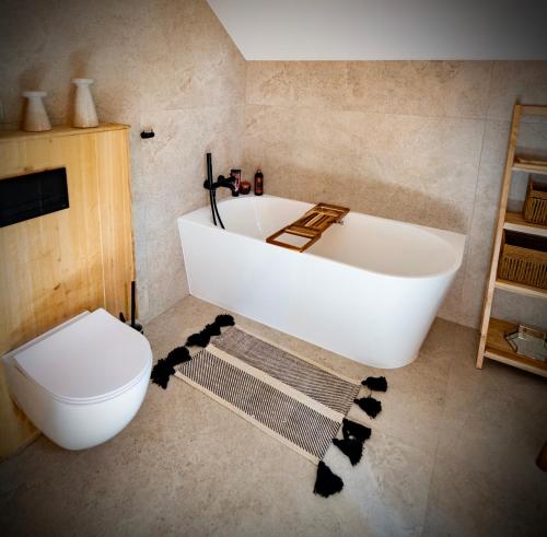 a bathroom with a white tub and a toilet at Gardiasówka na Roztoczu in Chlewiska