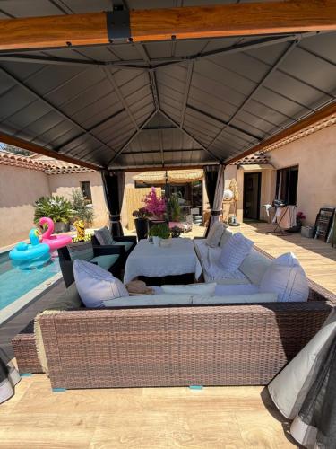a patio with a couch and chairs under an umbrella at Studio piscine in Bouc-Bel-Air