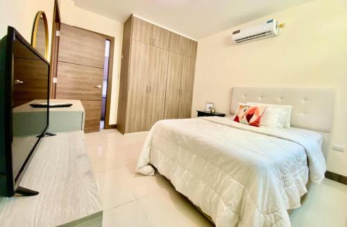 a bedroom with a white bed and a television at Lovely 2BD City Condo with parking in Guayaquil