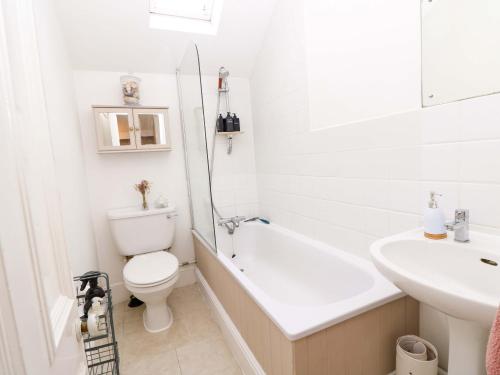 a white bathroom with a toilet and a sink at Fern Cottage in Bembridge