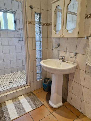 a bathroom with a sink and a shower at Villa Sardinia Guest House in Midrand