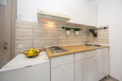 a white kitchen with a bowl of fruit on a counter at Apartments Milas in Okrug Gornji