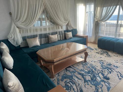 a living room with a blue couch with a coffee table at Villa MANSOURA avec piscine privative in Driouch