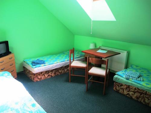 a room with two beds and a desk and a table at Hotel U Lišky in Hošťka