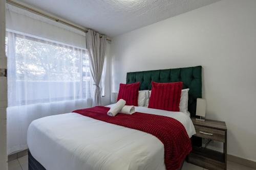 a bedroom with a large bed with red pillows and a window at Safi Self-Catering Suite 1 in Bunkers Hill