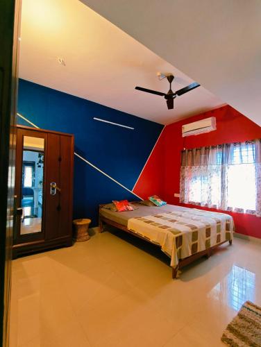 a bedroom with a bed with a blue and red wall at Phoenix Villa in Kappil