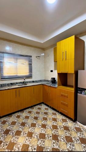an empty kitchen with wooden cabinets and a refrigerator at IFY LUXURY APARTMENTs in Maitama