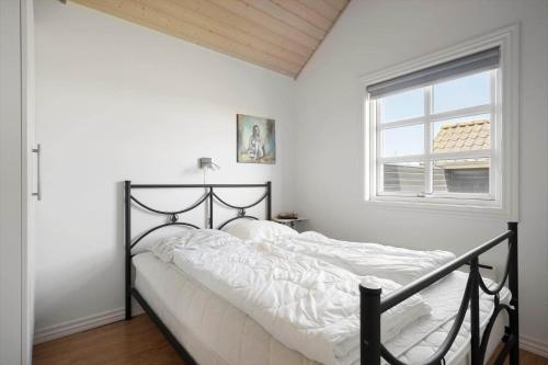 a bedroom with a bed with white sheets and a window at 2219-Ringkobing-Frans-Julius-Vej-2 in Søndervig