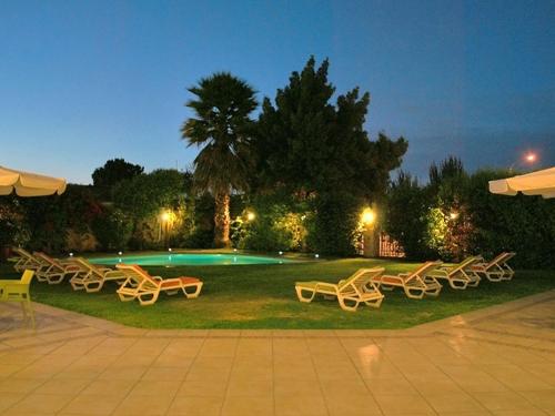 un grupo de sillas sentadas en el césped cerca de una piscina en Hotel Costa Real, en La Serena