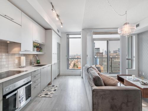 a kitchen and living room with a couch and windows at Atlantis Suites The Entertainment District - Toronto in Toronto