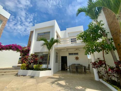 a white house with palm trees and flowers at Gorgeous Beach house 3BD Pool and BBQ in Punta Blanca