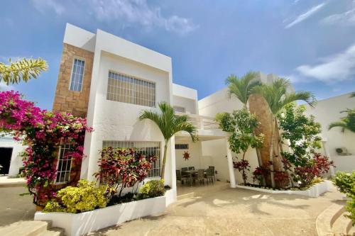 a white house with flowers and palm trees at Gorgeous Beach house 3BD Pool and BBQ in Punta Blanca